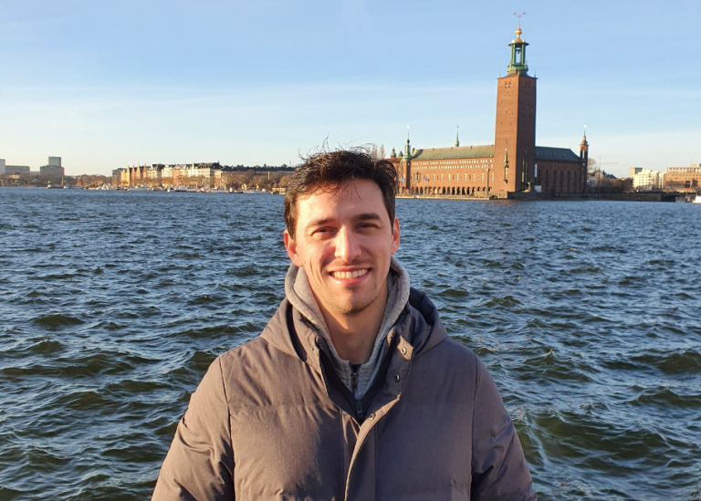 A photo of Guilherme Tácito de Luna in front of lake Mälaren and the Stockholm City Hall