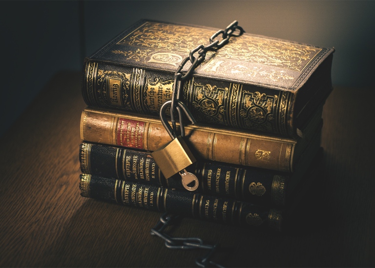 A pile of books surrounded with a chain which lock is open.