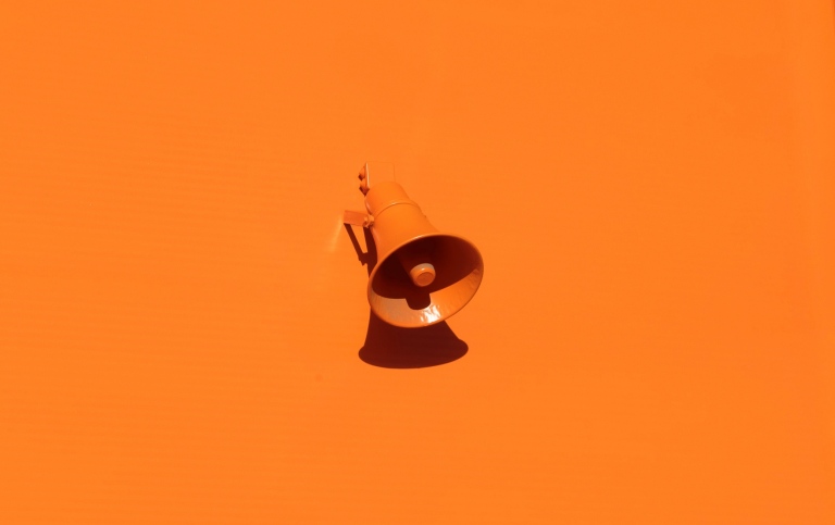 Megafon på orange vägg. Foto Oleg Laptov/Unsplash