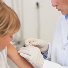 En läkare injicerar medicin i ett barns arm.