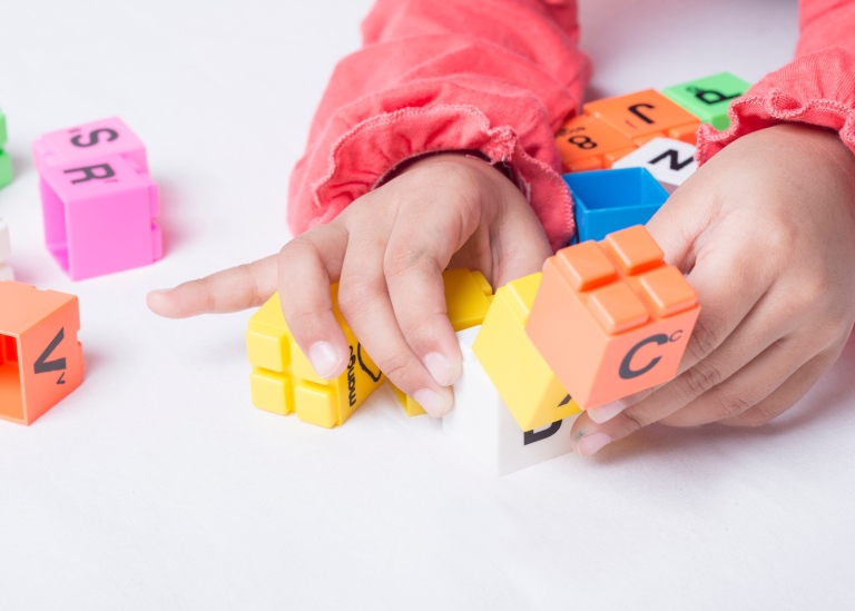 Barnhänder som leker med bokstäver