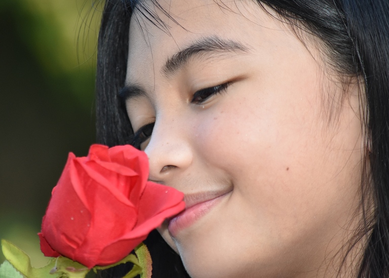 Flicka som luktar på ros.