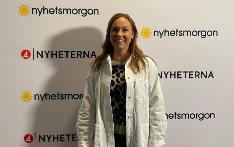 Johanna står framför vägg med Nyhetsmorgon- och TV4 Nyheterna-loggor
