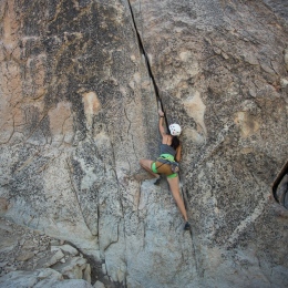 En kvinna klättrar upp för en bergsvägg