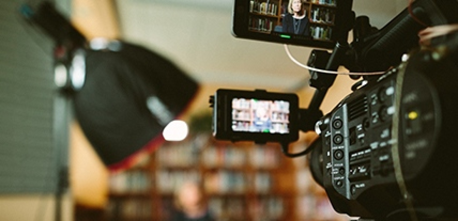 Kamera som filmar person som håller föreläsning bland bokhyllor