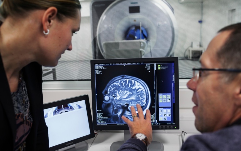 Två personer studerar en skärmbild från hjärnavbildning i magnetkamera
