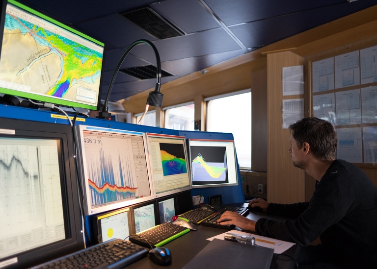 Christian Stranne in front of 5 screens working with bathymetry data on icebreaker oden