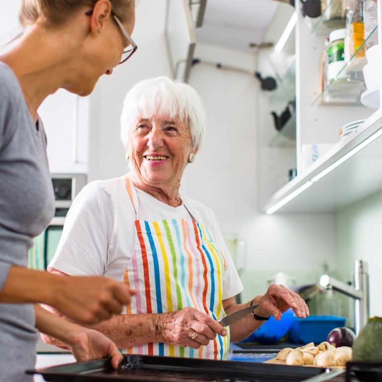Foto av äldre kvinna i kök som samtalar med en yngre kvinna
