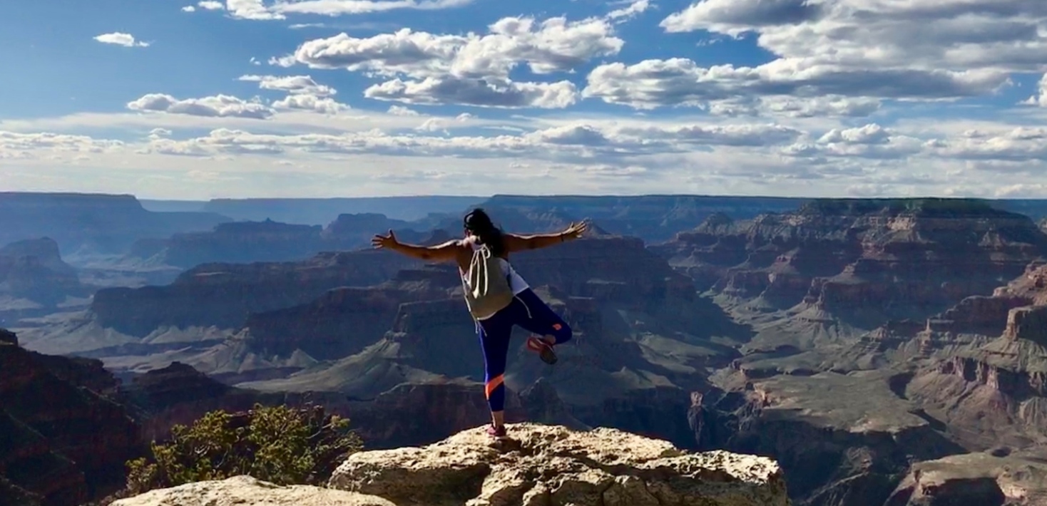 Person står och balanserar på ett ben vid Grand Canyon
