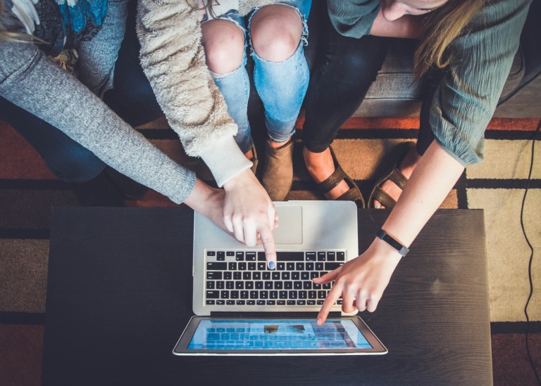 Three people in front of a computer. Photo: John Schnobrich/Unsplash