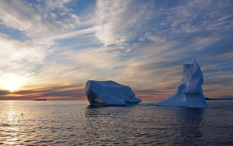 two smaller icebergs, greenland, with sunset on the left side