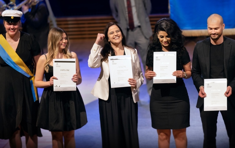 Fyra studenter har fått diplom, den andra från vänster håller upp handen i en segergest.