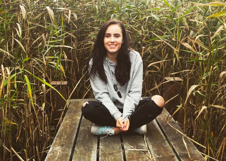 Deborah Suter, utbytesstudent från Schweiz sitter på en brygga med vass bakom sig.