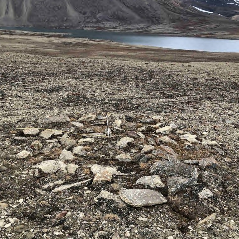 archaeological site, big and small stones scattered around, lake in the background