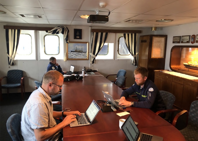 3 researchers sitting and writing onboard icebreaker Oden