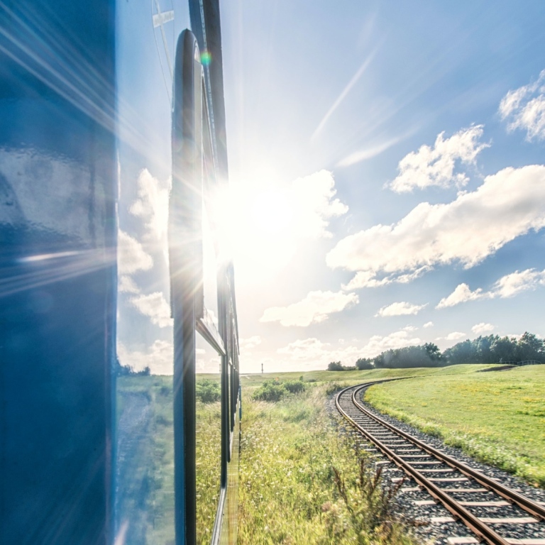 Tåg med utsikt mot en solig sommardag. Foto av Frenjamin Benklin på Unsplash.
