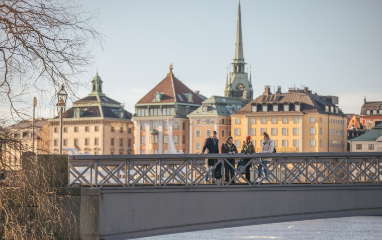 Fyra studenter står på en bro som leder till Skeppsholmen, Stockholm.