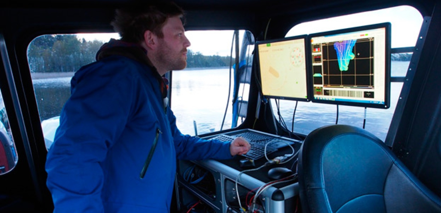 person looking at two screens inside a little research vessel. Photo: Private