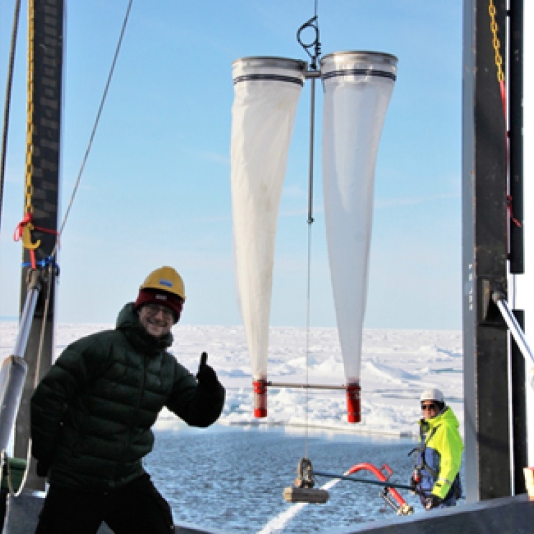 Research duing thums up on deck, icebreacker Oden, during deployment of a funnel-like net.