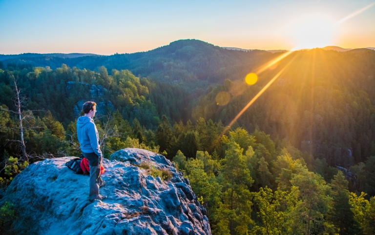 En person står vid en utkiksplats och tittar ut över ett naturreservat i soluppgång