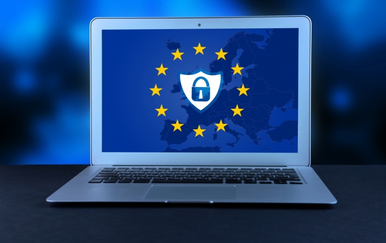Lock icon and shield icon on the background of the EU flag, on the laptop screen