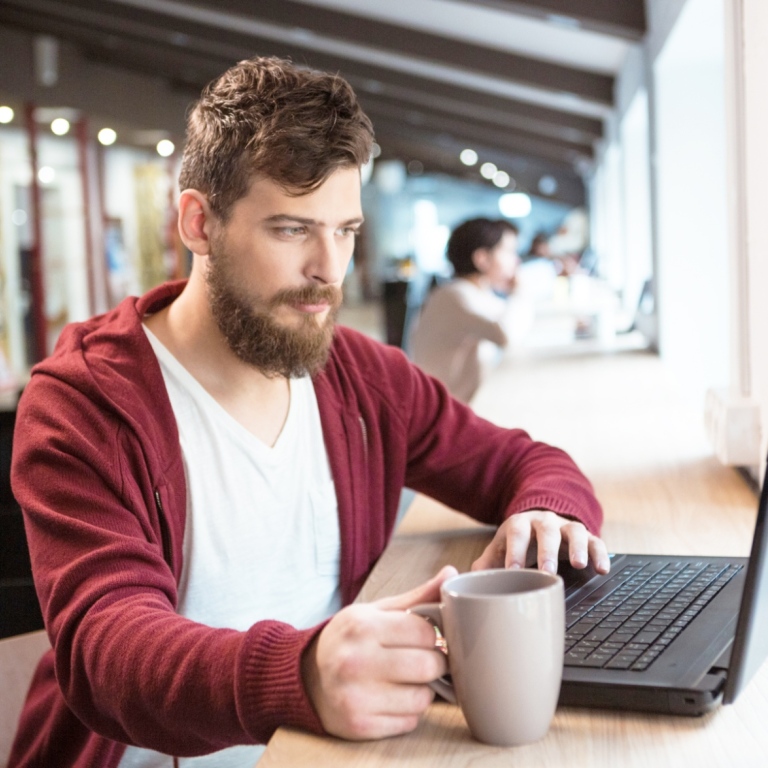 Ung man med laptop och kaffekopp