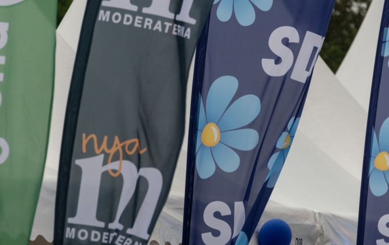 Reklamflaggor för Moderaterna och Sverigedemokraterna.