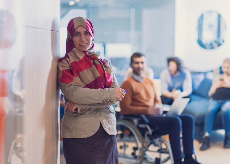 Muslim woman standing in front of a man in a wheelchair