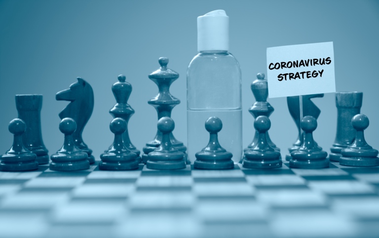 Coronavirus concept image chess pieces and hand sanitizer on chessboard