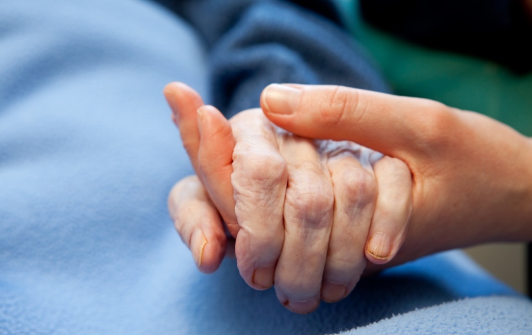 Genrebild: En äldre och en yngre person håller varandra i handen. Foto: Doug Olsen/Mostphotos.