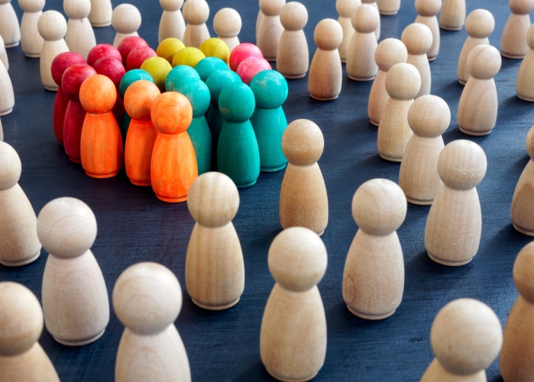 Social inclusion concept image - coloured figurines standing in group.
