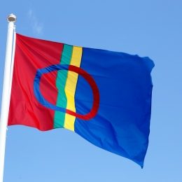 Samisk flagga som vajar mot en blå himmel.