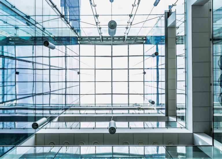 Genre photo: A building with several floors and glass ceiling, seen from the inside and looking up.