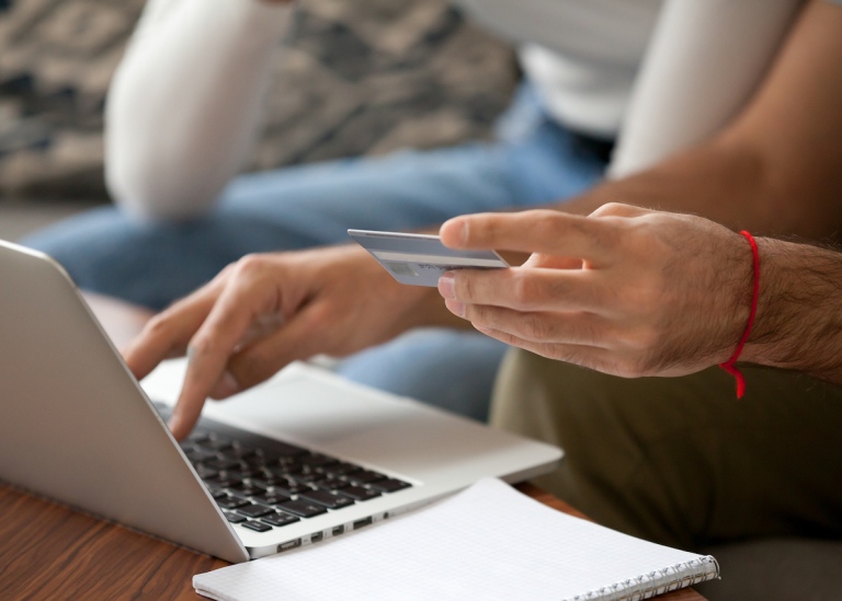Genre photo: Two persons shopping online with credit card, illustrating research in "Cyber Security"