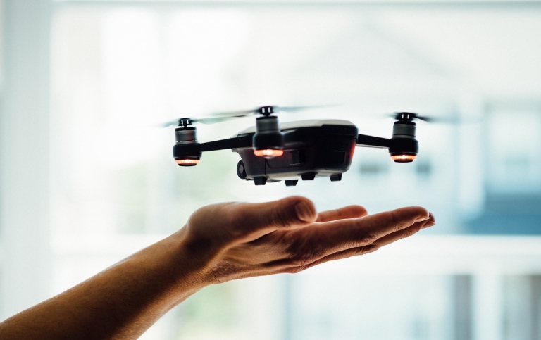 Genre photo: A person holding their hand under a drone flying. Illustrates research.