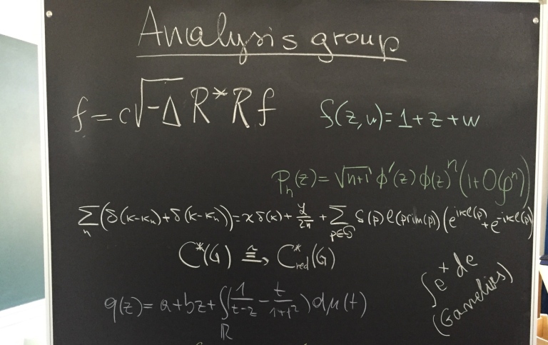 Svart tavla med rubrik "Analysis group" och matematiska formler.
