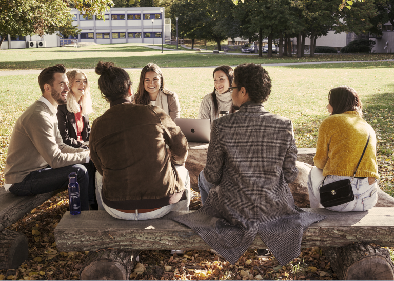 A group of students sitting on the grass field at Frescati campus.