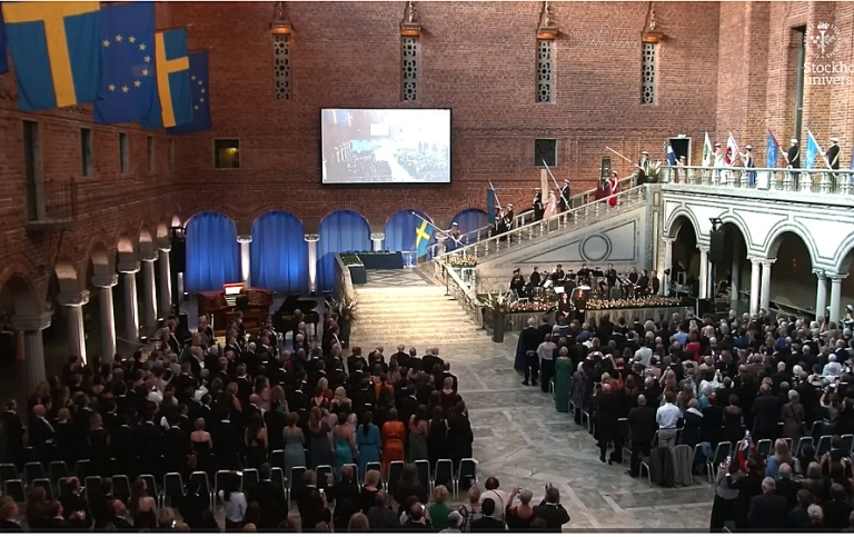 Fanbärarna går ned för trappan inför åhörare i Blå hallen i Stockholms stadshus.