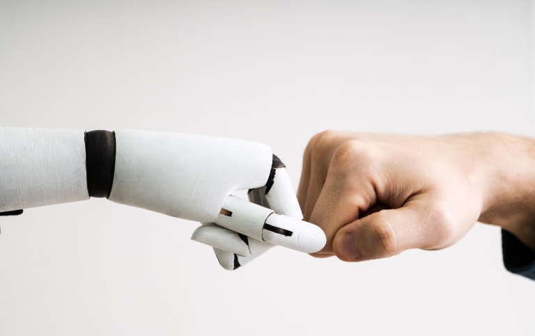 Genrebild: en robothand och en mänsklig hand möts i en fistbump. Foto: Andrey Popov/Mostphotos.