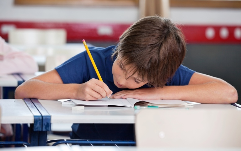 Schoolboy is writing at his desk. Photo: Doug Olson, MostPhotos
