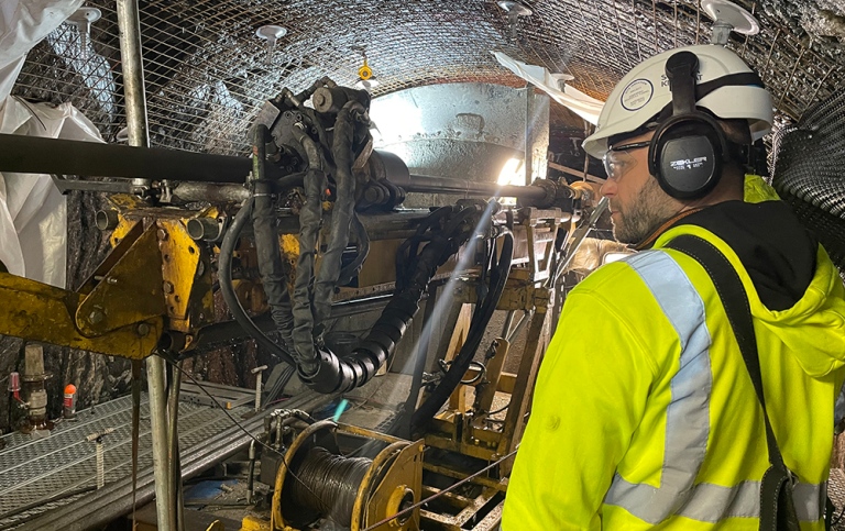 En man i skyddskläder intill borrmaskinen i en tunnel.