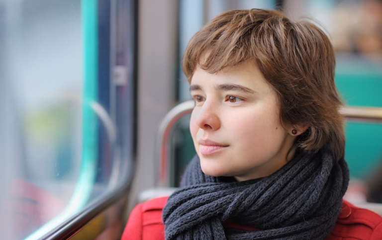 A young woman sitting by a train window.