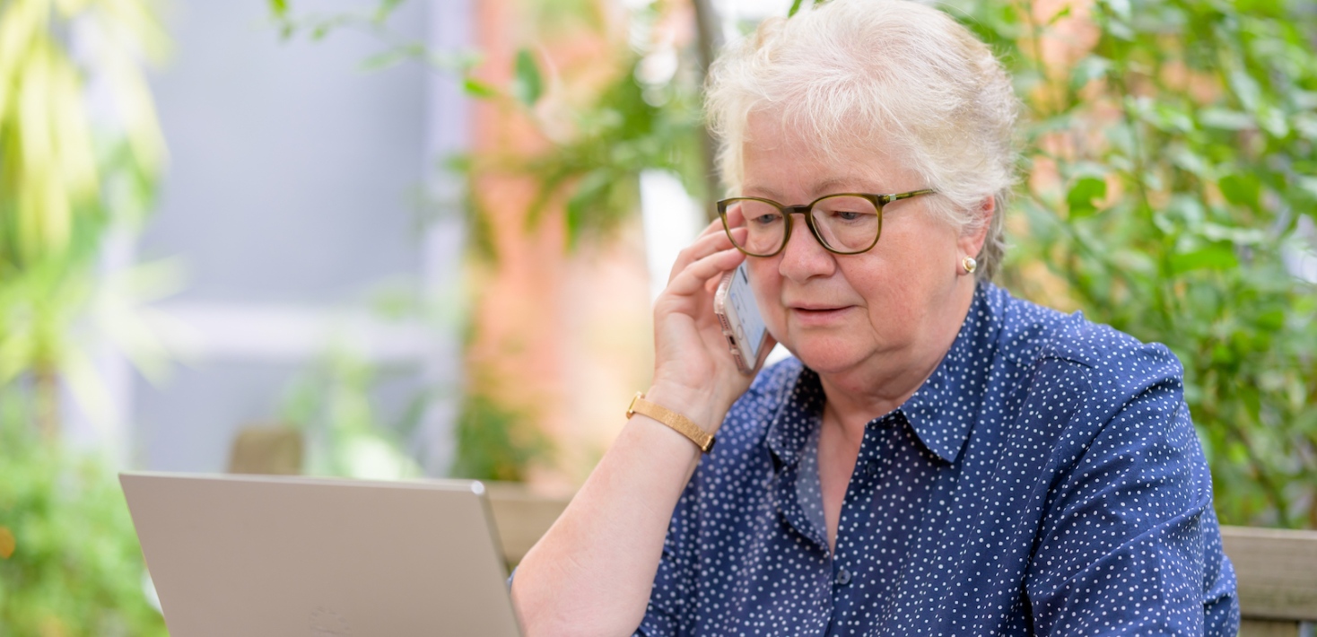 An elderly woman on the phone in front of a laptop. A photo from the Age-positive image library.