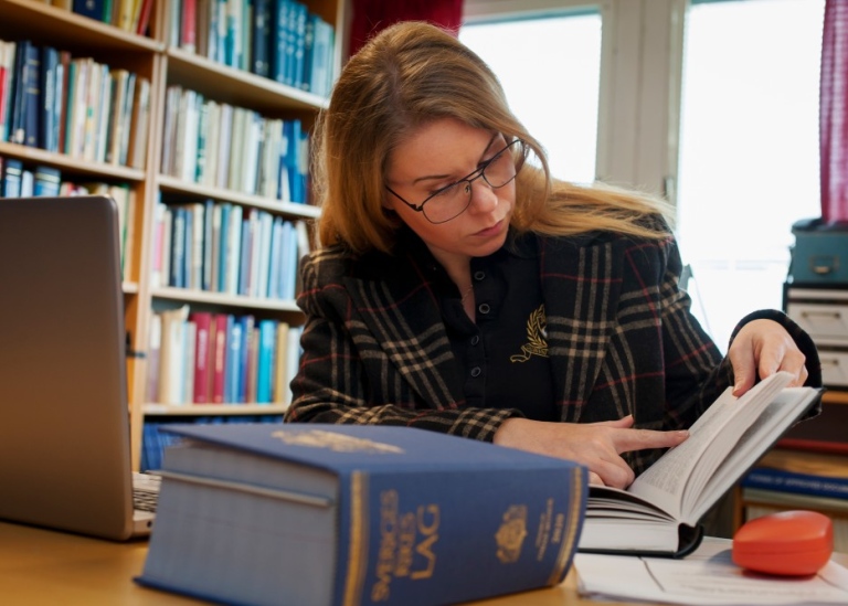 Kvinna i ett institutionsbibliotek som läser juridisk litteratur