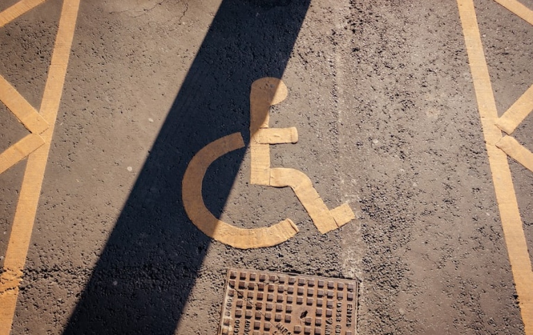 A handicapped sign painted on the asphalt of a parking lot