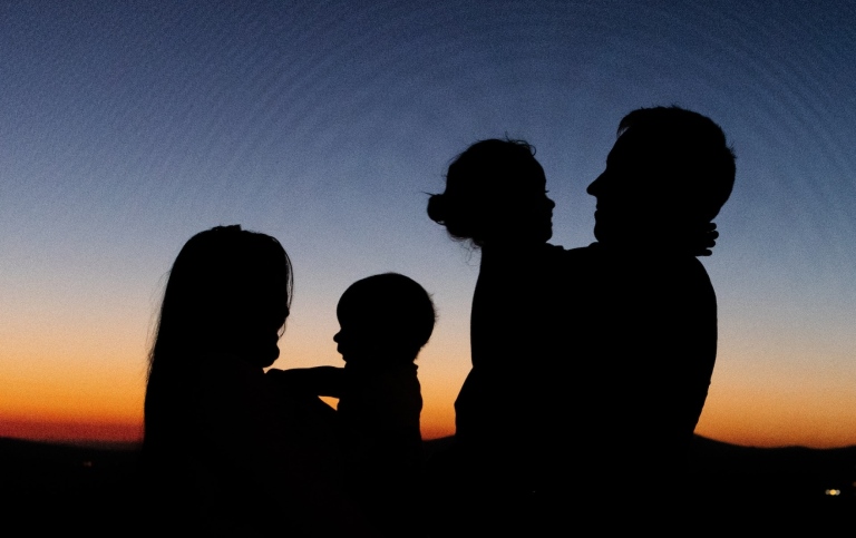 Silhouette of a family standing during sunset