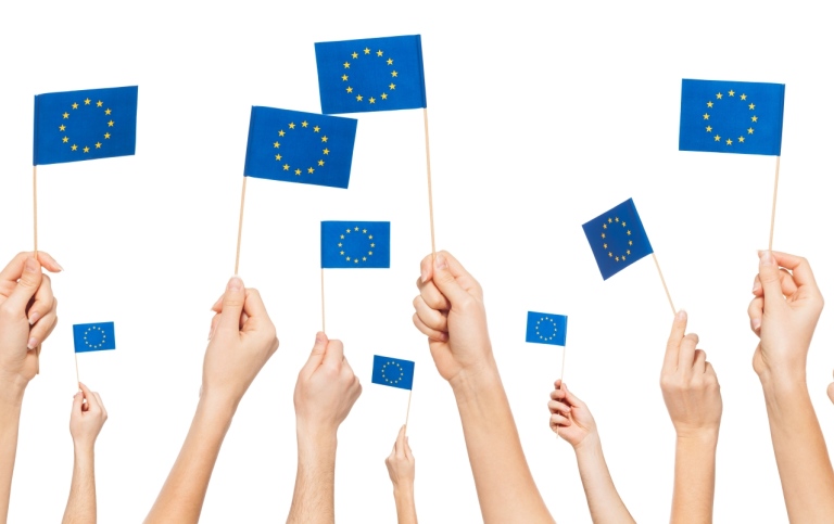 HANDS HOLDING AND RAISING EUROPEAN UNION FLAGS