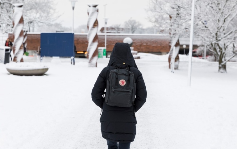 Student walking towards the tube station in the snow.