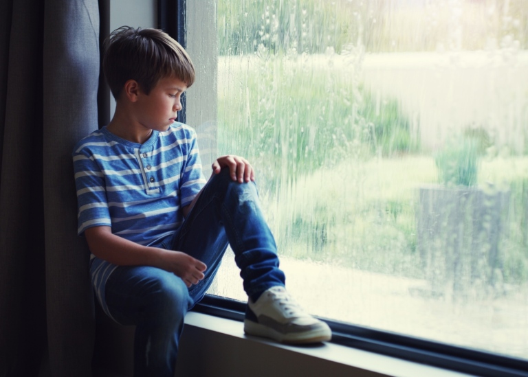 Pojke som sitter i ett fönster