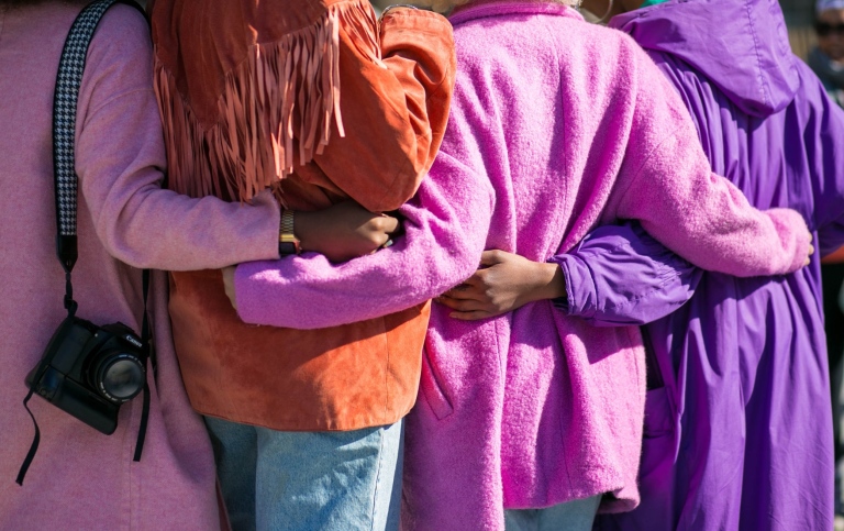 Young people in colorful clothes hold each other
